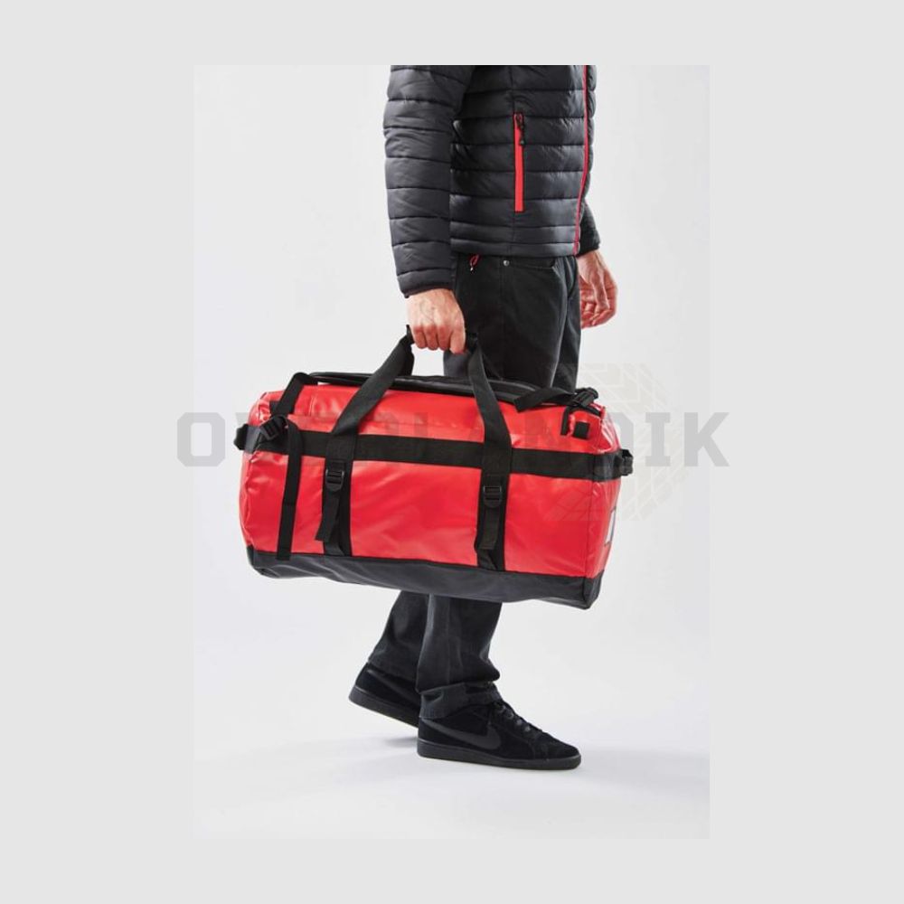 Bolsa de viaje Atlantis de Stormtech de 89L con correas de mochila, en rojo, vista con modelo